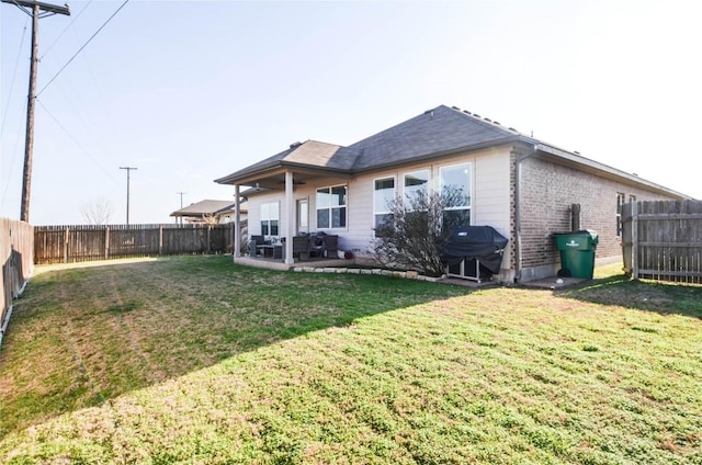 back of property featuring a patio, a yard, a fenced backyard, and brick siding