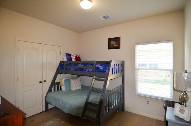 bedroom with wood finished floors, visible vents, and baseboards