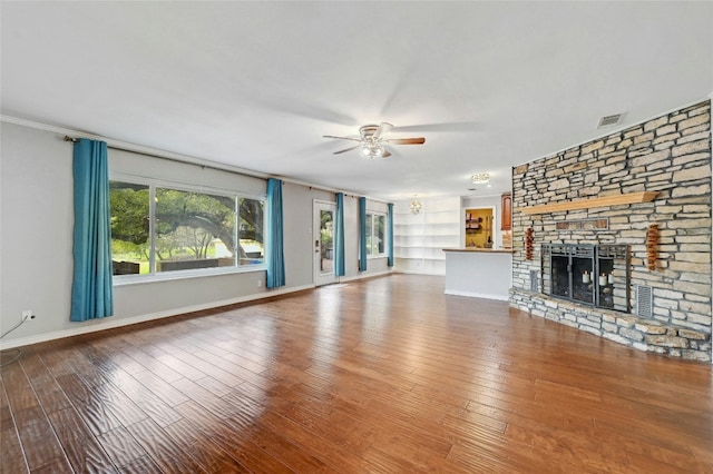 unfurnished living room with visible vents, baseboards, built in features, hardwood / wood-style floors, and a fireplace