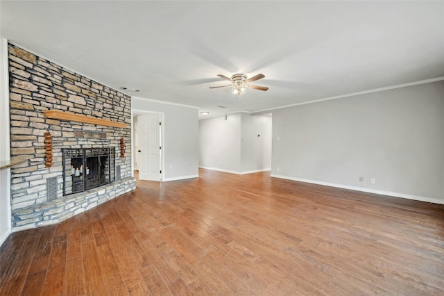 unfurnished living room featuring ceiling fan, ornamental molding, wood-type flooring, and a large fireplace