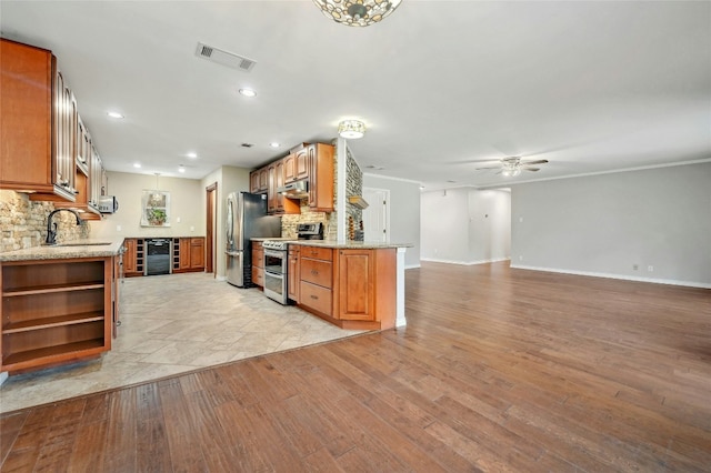 kitchen featuring beverage cooler, visible vents, light wood finished floors, decorative backsplash, and appliances with stainless steel finishes