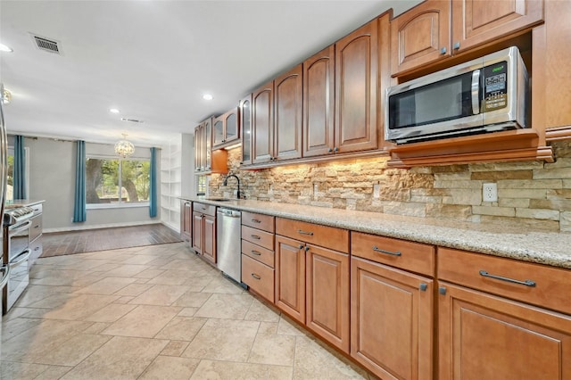 kitchen featuring light stone countertops, visible vents, decorative backsplash, appliances with stainless steel finishes, and brown cabinets