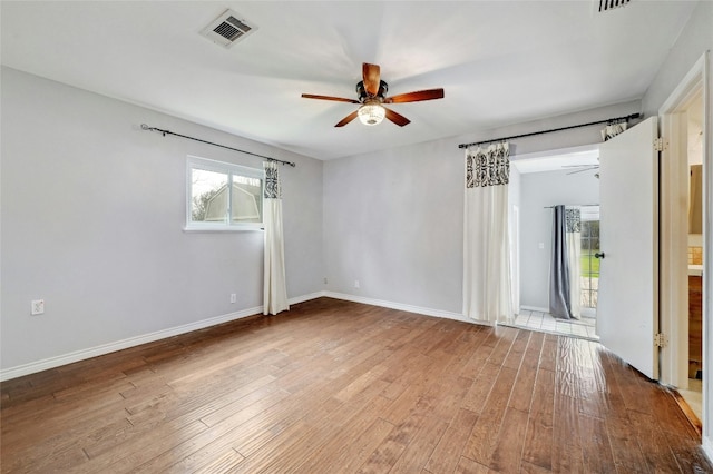 spare room with a ceiling fan, wood finished floors, visible vents, and baseboards