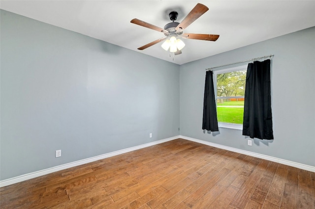 unfurnished room with a ceiling fan, wood finished floors, and baseboards