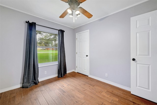 unfurnished room featuring hardwood / wood-style floors, a ceiling fan, and baseboards