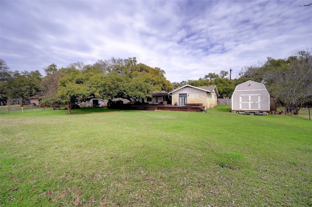 view of yard with a storage shed, fence, an outdoor structure, and a wooden deck