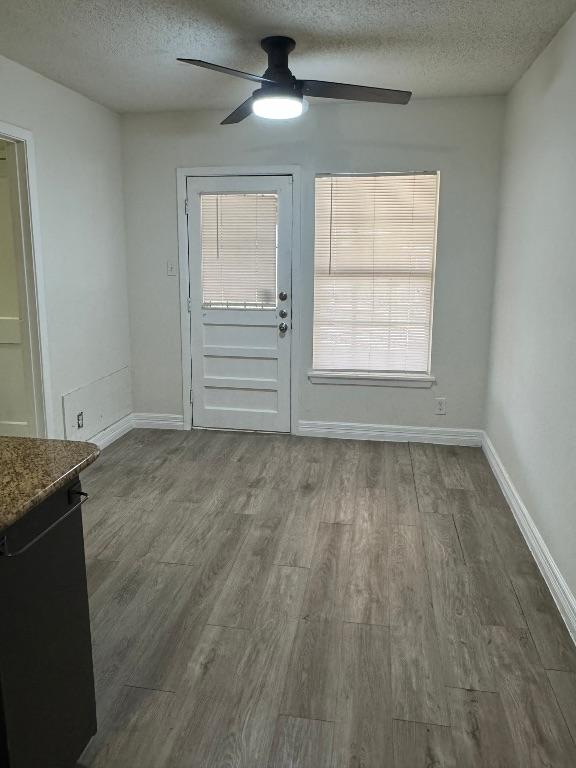 interior space with dark wood-type flooring, a ceiling fan, baseboards, and a textured ceiling