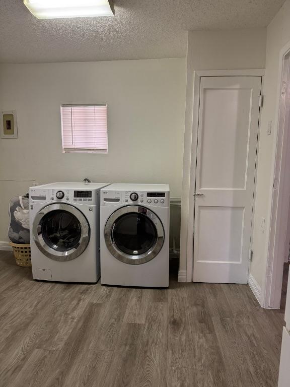 laundry area featuring a textured ceiling, wood finished floors, laundry area, and washer and clothes dryer