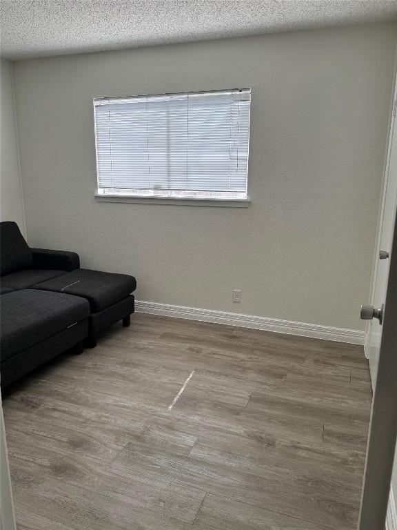 interior space featuring baseboards, a textured ceiling, and wood finished floors