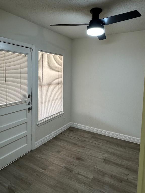 empty room featuring ceiling fan, dark wood-style floors, baseboards, and a textured ceiling