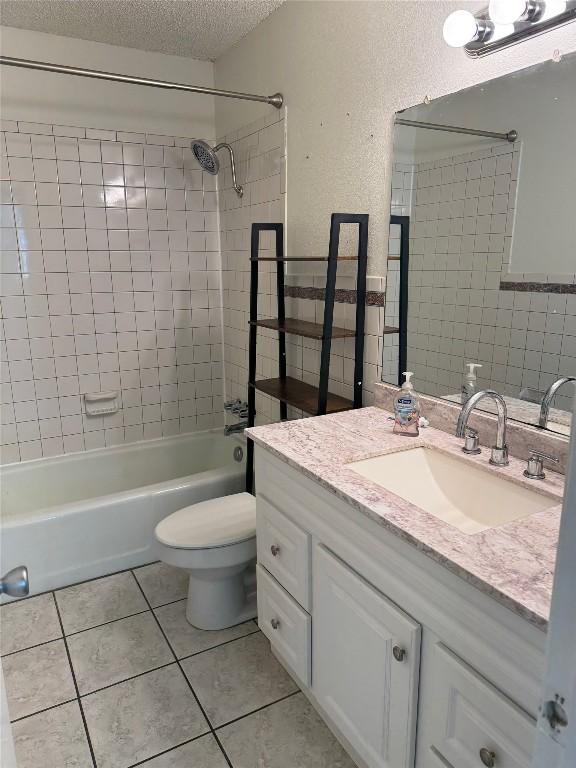 bathroom featuring tile patterned flooring, toilet, shower / tub combination, a textured ceiling, and vanity