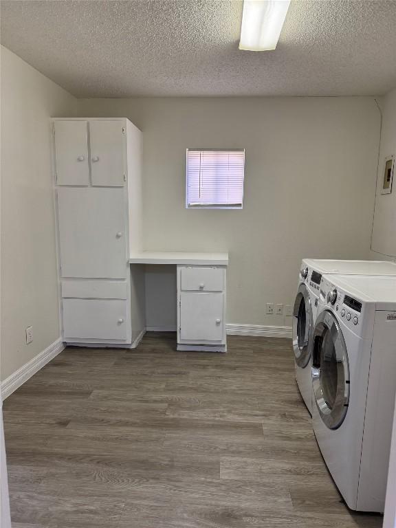 washroom featuring baseboards, cabinet space, independent washer and dryer, and wood finished floors