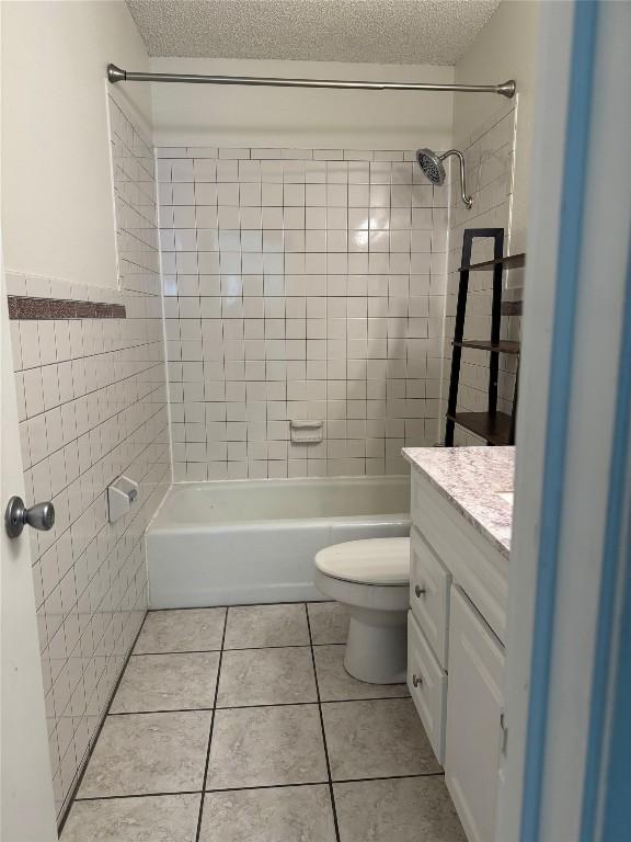 full bathroom featuring tile patterned flooring, tile walls, toilet, a textured ceiling, and vanity