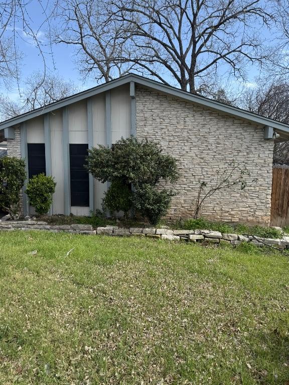 view of side of home with a yard and stone siding