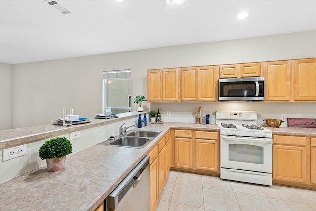 kitchen featuring light tile patterned floors, light brown cabinets, a sink, light countertops, and appliances with stainless steel finishes