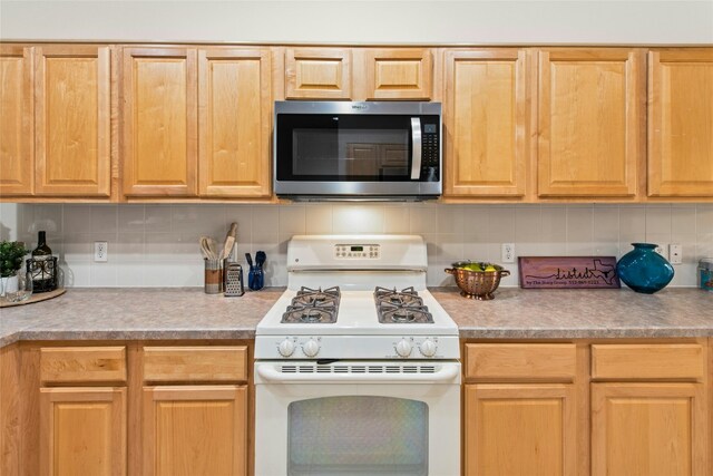 216 Farm Hill Dr, Georgetown, TX 78633 - kitchen with stainless steel microwave, white gas stove, backsplash, light countertops, and light brown cabinetry
