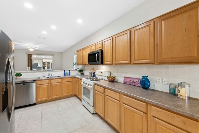 kitchen with a ceiling fan, a sink, dark countertops, stainless steel appliances, and light tile patterned floors