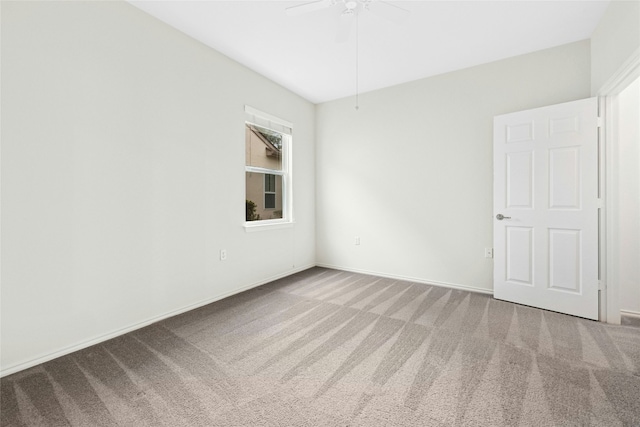 carpeted spare room featuring baseboards and a ceiling fan