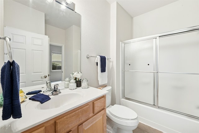 bathroom featuring enclosed tub / shower combo, tile patterned flooring, toilet, and vanity