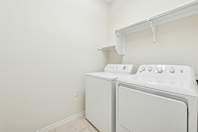 clothes washing area with light tile patterned flooring, laundry area, independent washer and dryer, and baseboards