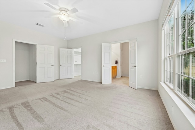 unfurnished bedroom with visible vents, light colored carpet, connected bathroom, and baseboards