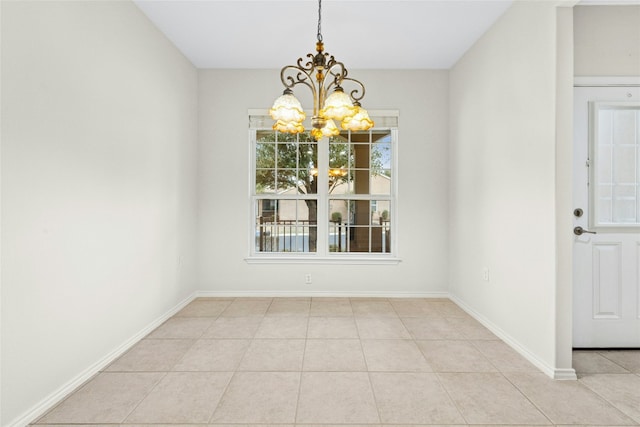 unfurnished dining area featuring tile patterned flooring, a notable chandelier, and baseboards