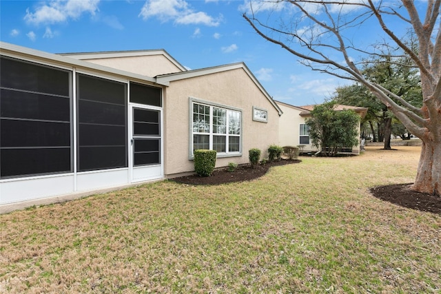 view of side of home with a lawn, a sunroom, and stucco siding