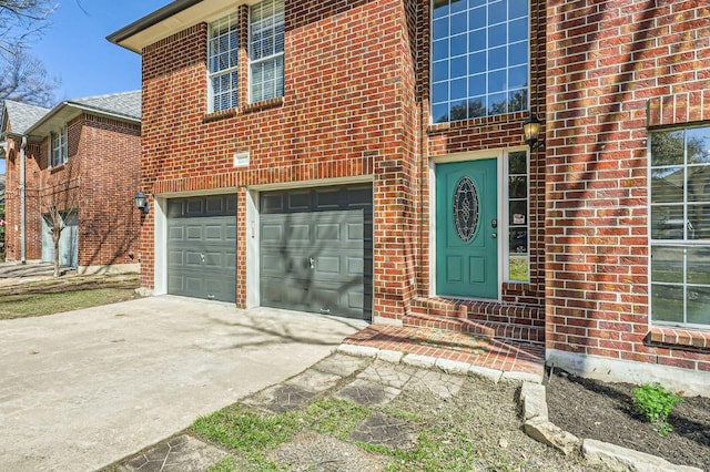 view of exterior entry featuring brick siding, concrete driveway, and an attached garage