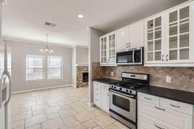 kitchen with dark countertops, stainless steel appliances, crown molding, and tasteful backsplash