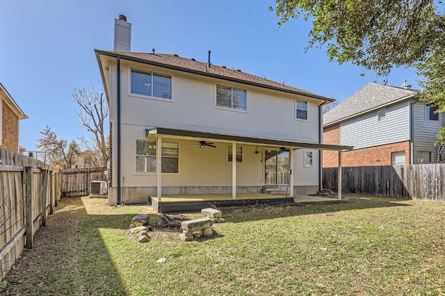 back of property with ceiling fan, a lawn, a chimney, a fenced backyard, and a patio area