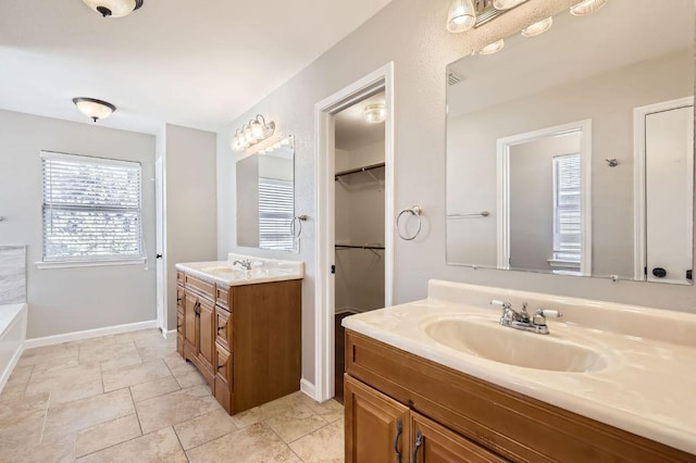 bathroom featuring a sink, baseboards, and two vanities