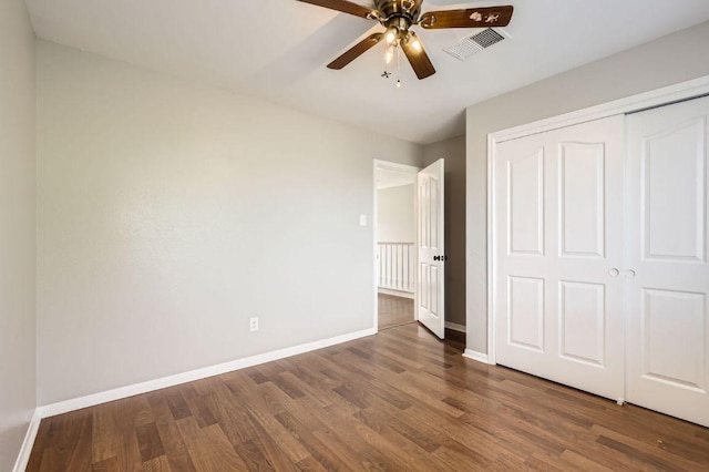 unfurnished bedroom with wood finished floors, visible vents, baseboards, ceiling fan, and a closet