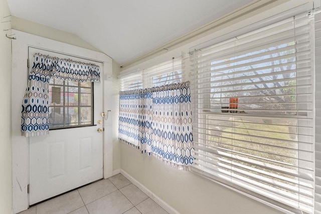 doorway featuring light tile patterned flooring, baseboards, and vaulted ceiling