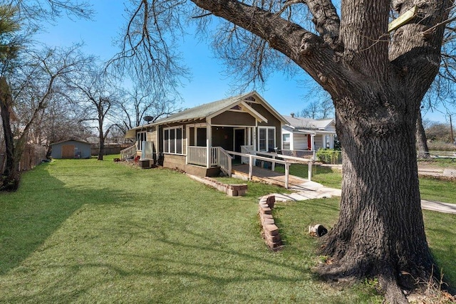 view of front of house featuring a front lawn, an outbuilding, fence, and a shed