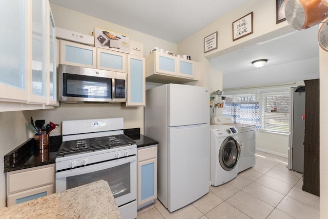 kitchen featuring white appliances, glass insert cabinets, light tile patterned floors, and washing machine and dryer