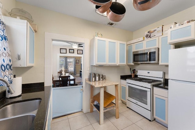 kitchen with glass insert cabinets, light tile patterned flooring, white appliances, a ceiling fan, and a sink