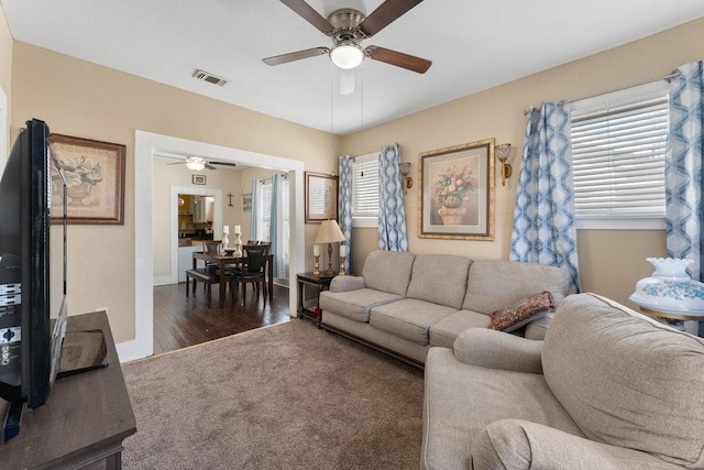 living area with visible vents, baseboards, wood finished floors, and a ceiling fan