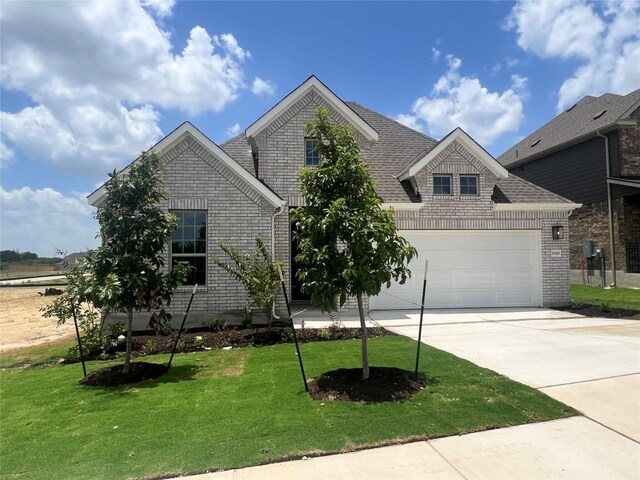 20425 Gillbrand Rd, Manor, TX 78653 - view of front of property with concrete driveway, a front lawn, brick siding, and a shingled roof