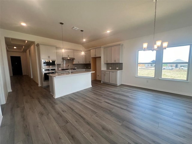 20425 Gillbrand Rd, Manor, TX 78653 - kitchen with stainless steel appliances, backsplash, dark wood-style flooring, an island with sink, and recessed lighting