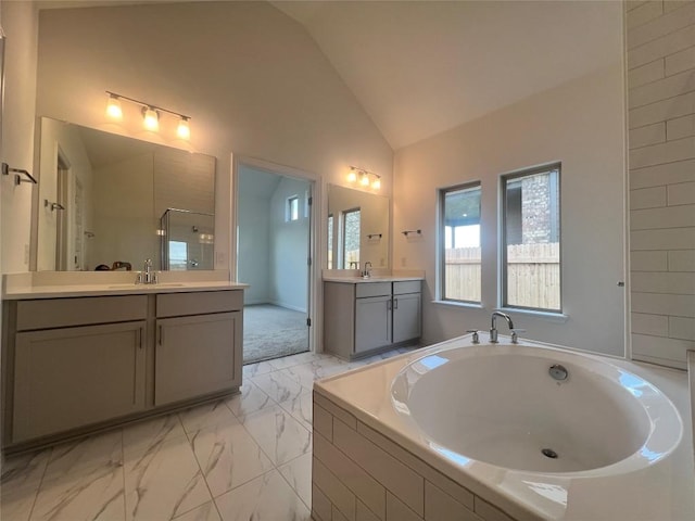 20425 Gillbrand Rd, Manor, TX 78653 - full bathroom featuring lofted ceiling, marble finish flooring, a garden tub, two vanities, and walk in shower