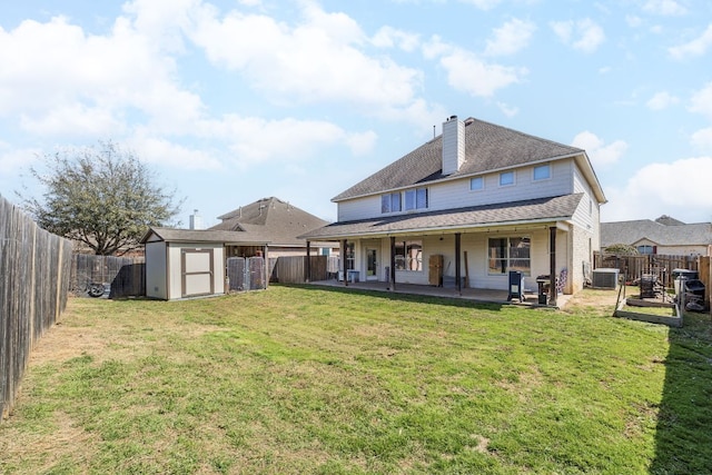 rear view of house with a storage shed, an outdoor structure, a yard, and a patio area