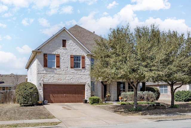 view of front of property with concrete driveway, an attached garage, fence, and stone siding