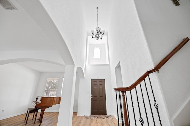 foyer entrance featuring arched walkways, a healthy amount of sunlight, light wood-style flooring, and stairs