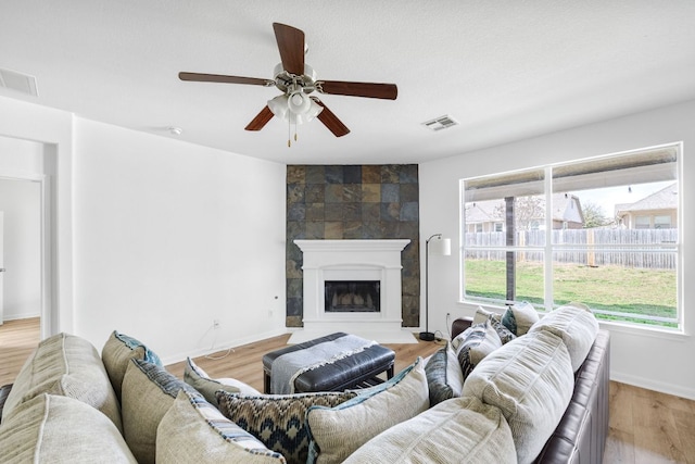 living area featuring visible vents, baseboards, light wood-style flooring, and a fireplace