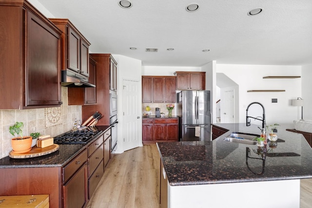 2246 Garlic Creek Dr, Buda, TX 78610 - kitchen featuring black appliances, light wood-style floors, a large island, decorative backsplash, and under cabinet range hood