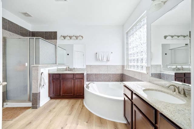 2246 Garlic Creek Dr, Buda, TX 78610 - full bathroom with a shower stall, wood finished floors, two vanities, and a bath