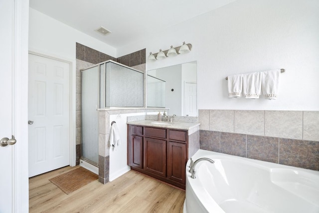 full bath with visible vents, wood finished floors, a bath, and a shower stall