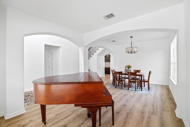 dining area with stairway, baseboards, visible vents, light wood finished floors, and a notable chandelier