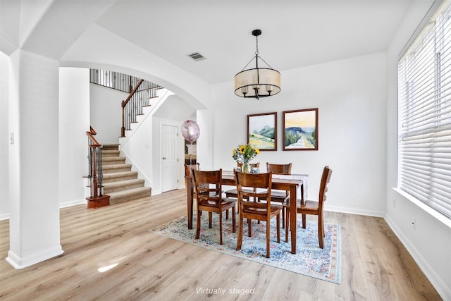 2246 Garlic Creek Dr, Buda, TX 78610 - dining room with light wood-style flooring, arched walkways, a chandelier, and stairway