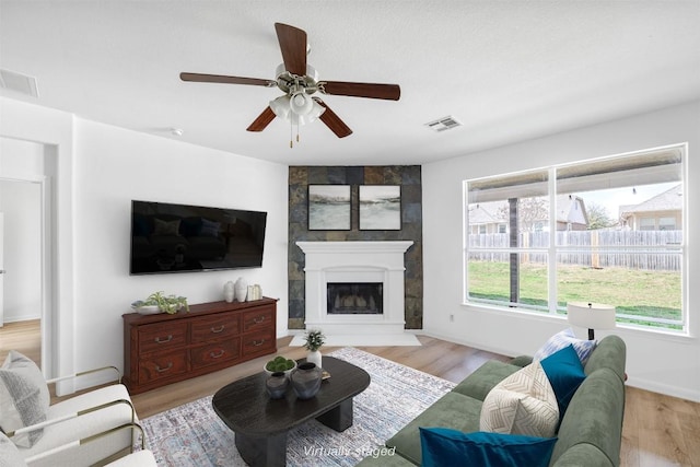 2246 Garlic Creek Dr, Buda, TX 78610 - living area with wood finished floors, a ceiling fan, and a large fireplace